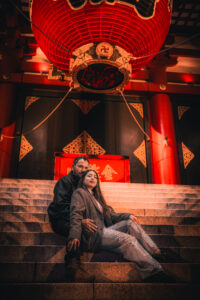 Couple Photography A couple sitting on steps in front of Sensoji Temple in Asakusa with large red lanterns and decorative elements.