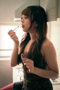 Cinematic Portrait A woman applying lipstick while looking at a mirror, with natural light illuminating her face.