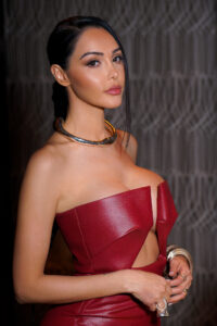 French Influencer Nabilla A famous influencer in a red strapless dress with a silver choker, posing confidently.