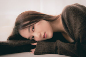 Studio Portrait of a Young Woman for a Model Portfolio Portrait of a young woman resting her head on her arms, wearing a cozy brown sweater, studio photography in Tokyo.