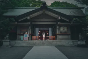 Tokyo Shrine: Traditional Japanese Culture Photography A person praying at the entrance of a traditional Shinto shrine in Tokyo, showcasing Japanese culture and architecture.
