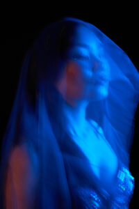 Creative Portrait A close-up portrait of a Tokyo dancer with long hair illuminated by blue light, creating a dramatic effect.