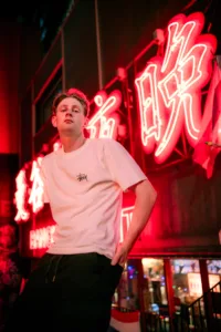 Tokyo Street Fashion: Neon Nightlife Portrait Young man posing in Tokyo street fashion with neon lights at night.