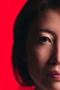 Moody close-up portrait featuring dramatic lighting and a bold red background.