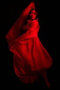 Artistic portrait of a person draped in flowing red fabric, dramatic lighting, fashion photography by JG Brasseur.