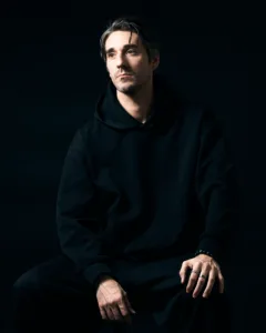 Male model wearing a black hoodie, captured in a moody fashion photography session in Tokyo.