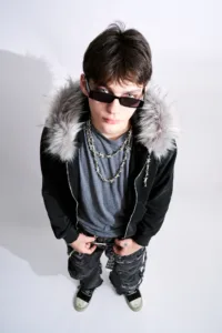 Post Xeno Streetwear – Fashion Portrait by JG Brasseur High-angle studio portrait of a model wearing a Post Xeno faux-fur hooded jacket, barbed wire necklaces, and distressed streetwear by Tokyo photographer JG Brasseur.