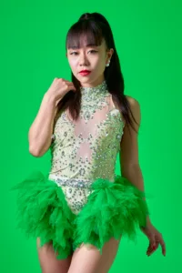 Bold Stage Portrait - Tokyo Studio Sessions Professional studio portrait of a female performer in a vibrant green sequined and ruffled stage outfit, posed against a bright green screen background in a Tokyo photography studio.